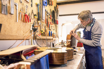 Instrument maker repairing an old acoustic guitar