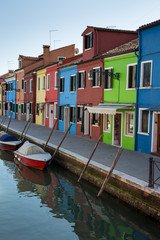 Fototapeta na wymiar A row of several brightly coloured buildings on the ede of a canal in Burano Italy