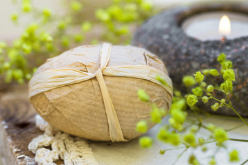 Handcrafted decorative Easter egg wrapped in craft paper, candle, flowers on lace napkin, vintage style