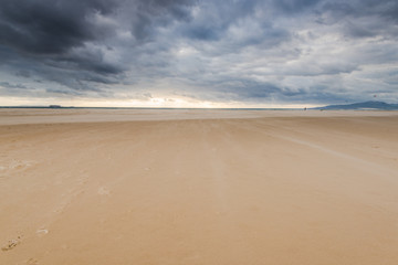 Fototapeta na wymiar stormy dark clouds over sand beach