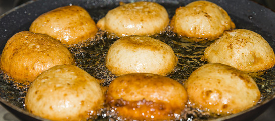 Donuts frying in deep fat. Preparation of traditional donuts
