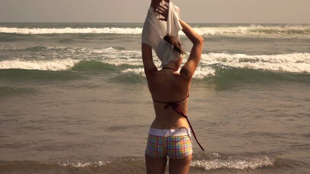 Woman taking off T-shirt near sea, super slow motion 240fps
