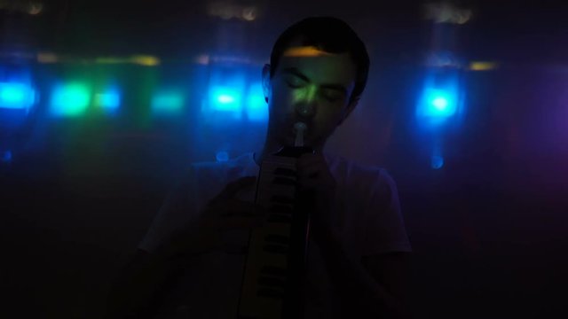 A young man playing the melodica in nightclub