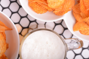 Glass of light beer and potato chips on a abstract background. top view