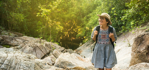 Portrait of beautiful young woman with backpack standing by the mountain. Female hiker hiking by the mountain trail.