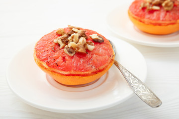 Baked grapefruit with walnuts on a white background. 