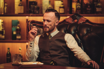 Confident upper class man smoking cigar in gentlemen's club