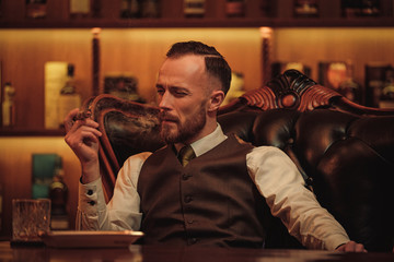Confident upper class man smoking cigar in gentlemen's club