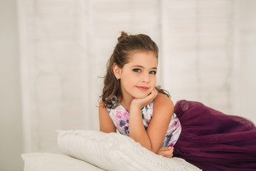 Fototapeta premium Beautiful girl in a purple dress and flower blouse posing for a photographer. Photosession for the magazine.