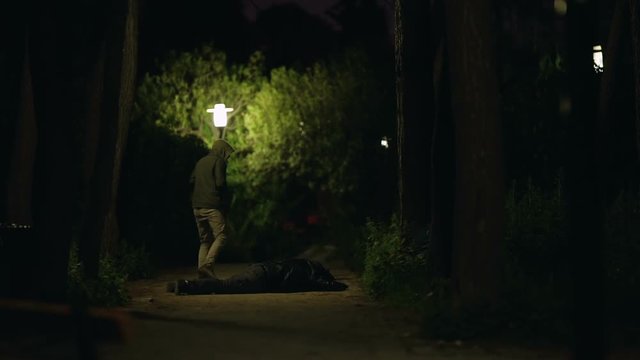 Murder on a dark urban park at night slomo.A man holding a knife flees the scene after the murder of another man on a dark park at night.