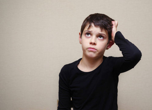 Portrait of the thought boy of the European appearance on a light background. Sarcastic look
