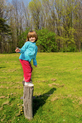 Little girl standing on the two big logs in the park