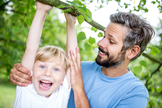Lachender Junge turnt an einem Baum