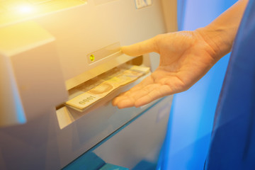 woman hand withdrawing money from indoor bank ATM,hand getting thai baht banknotes at ATM machine in the bank.selective focus,vintage color