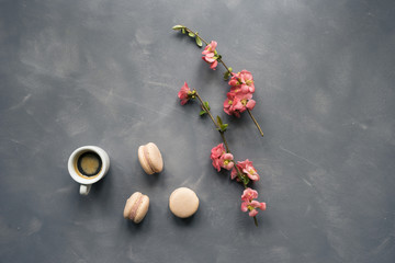 Top view of coffee, macarons and flowers on cement background