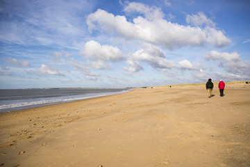 sandy beach in Vendee, France with blue sky and white clouds and people wandering