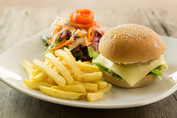 hamburger with vegetables and fries on a wooden board, side view..
