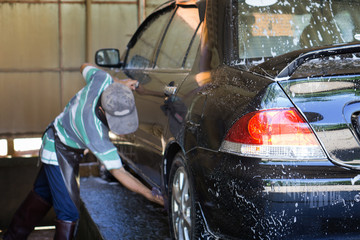 car washing by hand using a foam preparation for polishing,cars in a carwash,selective focus