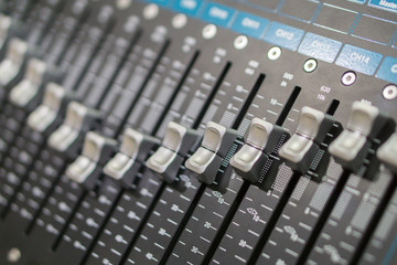 Side closeup on a sliders of a mixing console. It is used for audio signals modifications to...