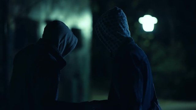 Two hooded men doing transaction at night,suspicious activity