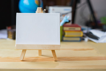 Easel with blank canvas on wooden table,Blank billboard on wood desk top with supplied bokeh background,Template mock up for montage of display your product.vintage color..