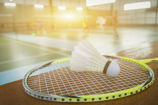 A set of badminton concept.Badminton ball (shuttlecock) and racket on court floor,Paddle and the shuttlecock and badminton courts with players competing in modern gym,selective focus,vintage color