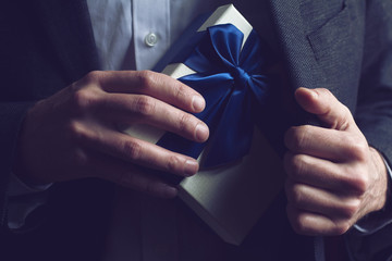 Man in suit opening a gift with blue ribbon