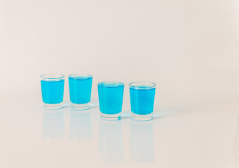Four glasses of blue kamikaze, glamorous drink, mixed drink poured into shot glasses