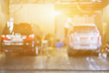 blurred background of Gentle Car Washing. Modern Compact Car Covered by Water. vintage Color Grading and Worker washing car in the car care blur for background.