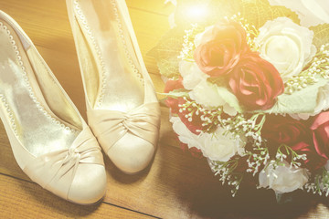 Wedding still life - Bridal bouquet and bride's shoes,beautiful white gold  shoes from bride on woodden,vintage color,selective focus.