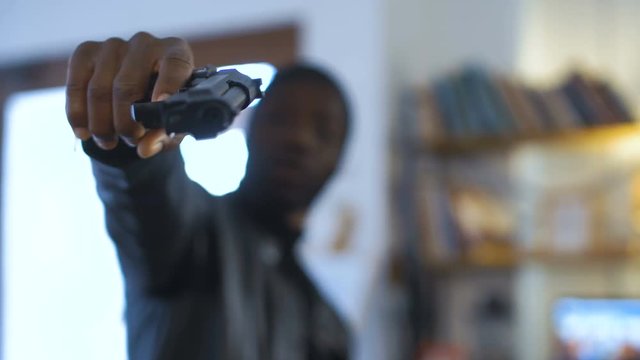 The blurred African robber aiming with the gun to the camera.