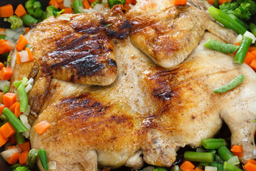 Whole grilled chicken with vegetables in a frying pan