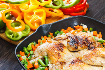 Whole grilled chicken on grill pan with vegetables and bell pepper