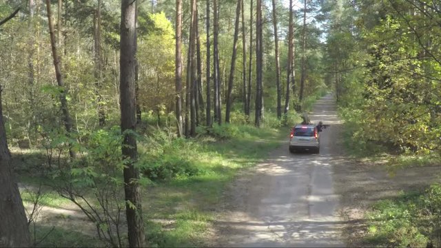 Flying over the car in forest. The quadcopter follows the jeep on the nature in forest. Aerial survey of jeep off-road. Car goes through the forest view