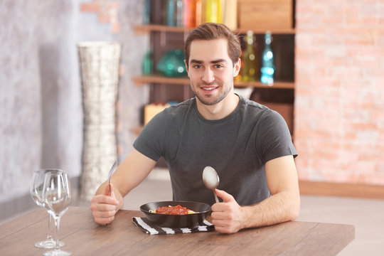 Young Man Eating Pasta At Table