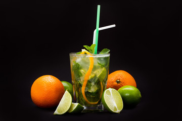 Mojito cocktail with straws and fruit on a black background
