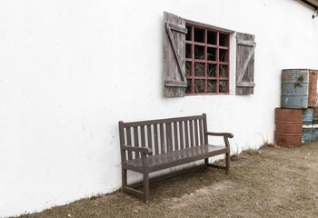 The bench is set against a white wall near a wooden window with a nearby oil tank.