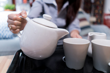 Tea poured from the white ceramic pitcher into a glass