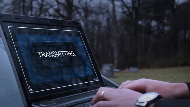 A secret agents transmits a message over a laptop