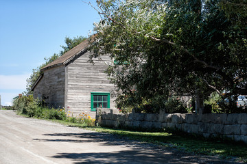 Older weathered small barn and rock wall along a country road