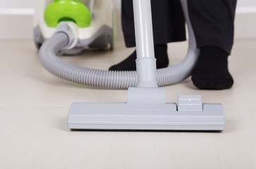 woman legs with vacuum cleaner cleaning floor