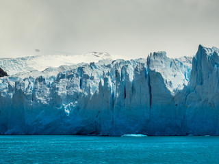 Massive glacier front above blue water