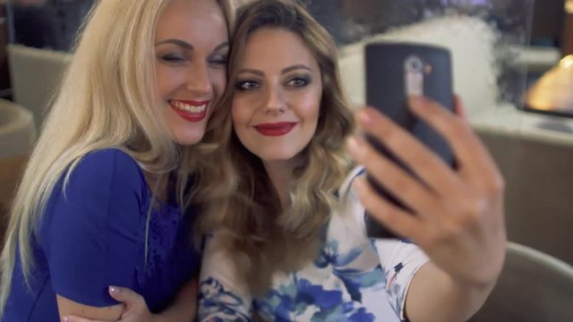 Friends girls taking selfie with a smart phone and making faces and fun