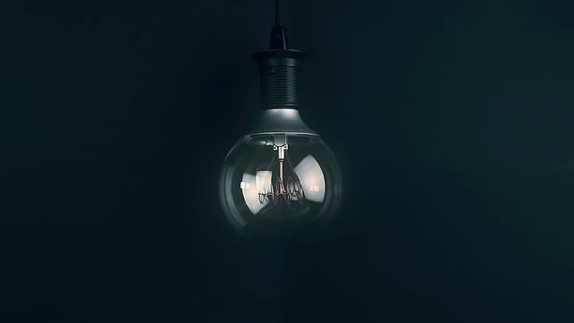 turn on and turn off, with blinking effect, retro vintage light bulb with led technology built-in on warm light yellow tint and black background, energy saving with old style atmosphere concept