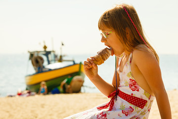 Toddler girl eating ice cream on beach