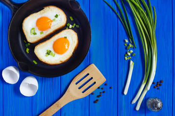 fried eggs and spring onion on blue wooden background