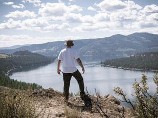 Fototapeta na wymiar Hiker Standing on Cliff Looking Out at Lake Roosevelt in Pacific Northwest