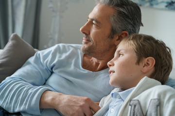 Obraz premium Portrait of father and son relaxing in sofa