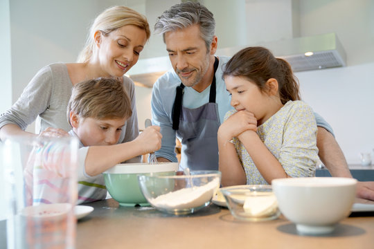 Family baking cake together in home kitchen
