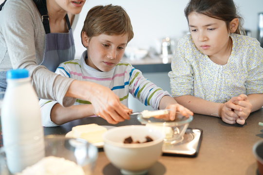 Mommy with kids baking cake together in home kitchen